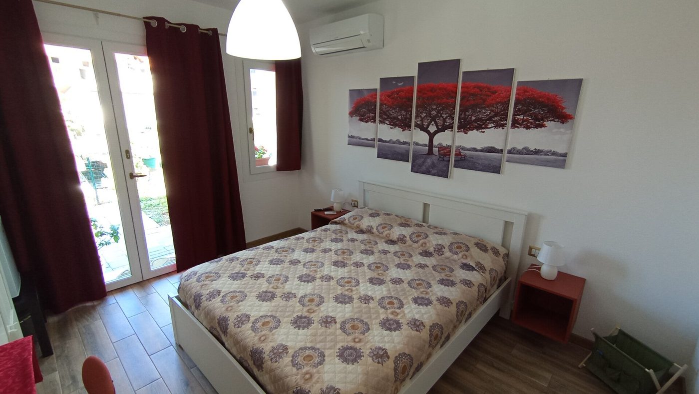 Camera 2: letto matrimoniale con quadro e porta finestra luminosa