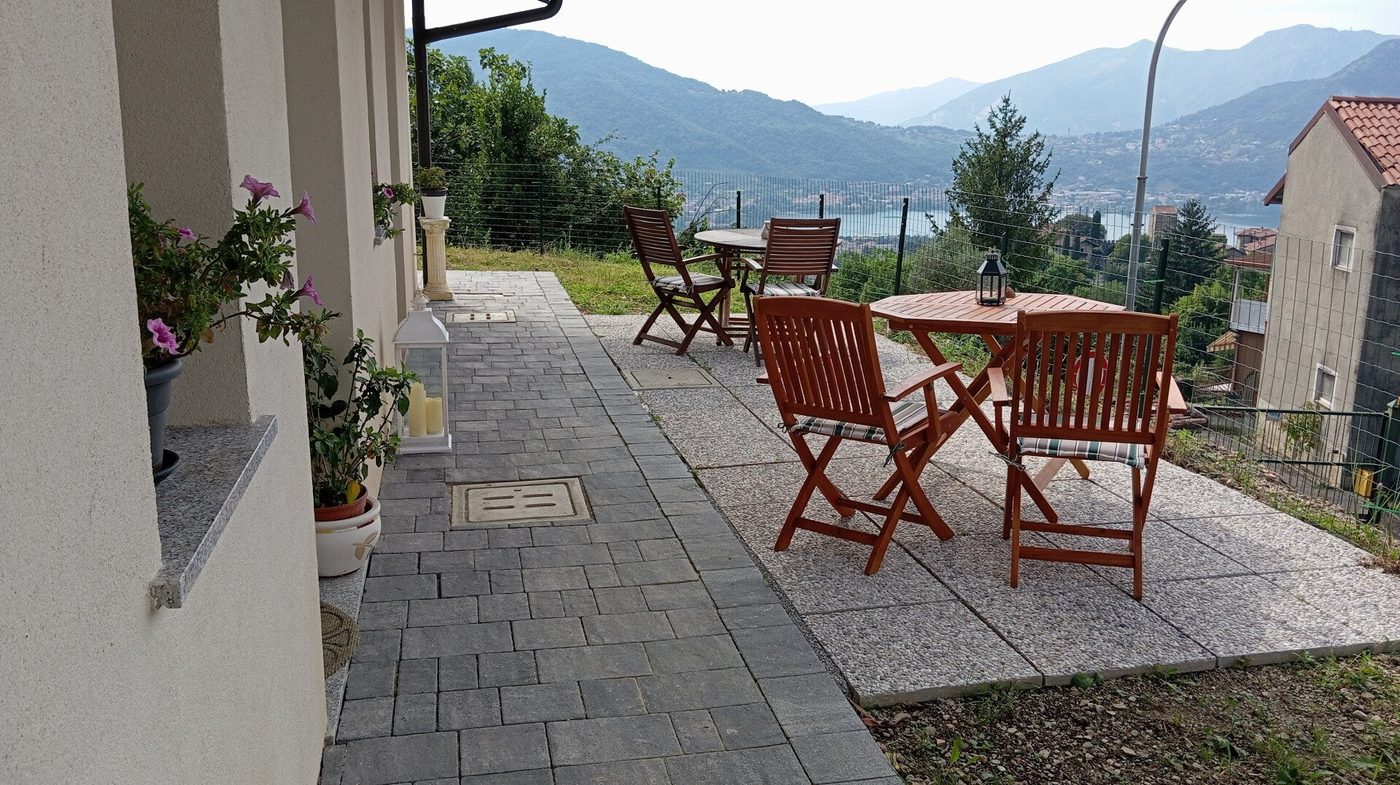 La terrazza della Dimora con tavolini in legno e vista sul lago