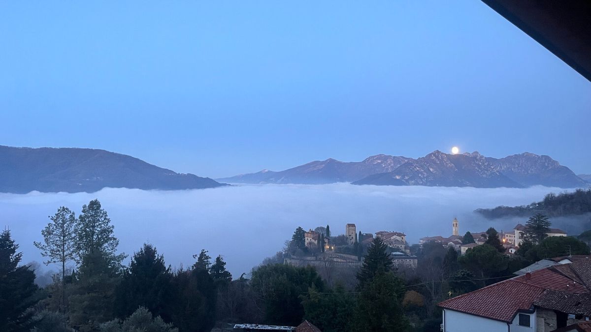 Mare di nebbia sul lago all'alba, con il castello che emerge
