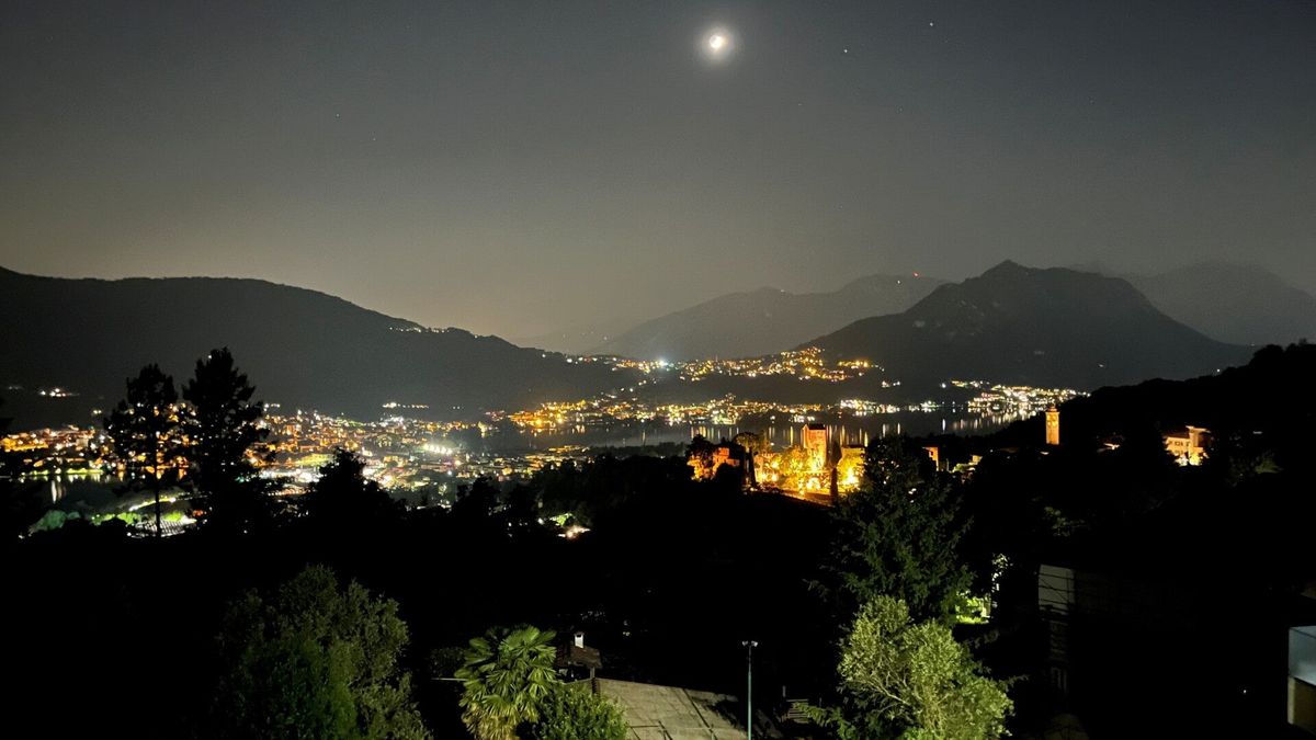 Le luci dei paesi sul lago di notte, con la luna